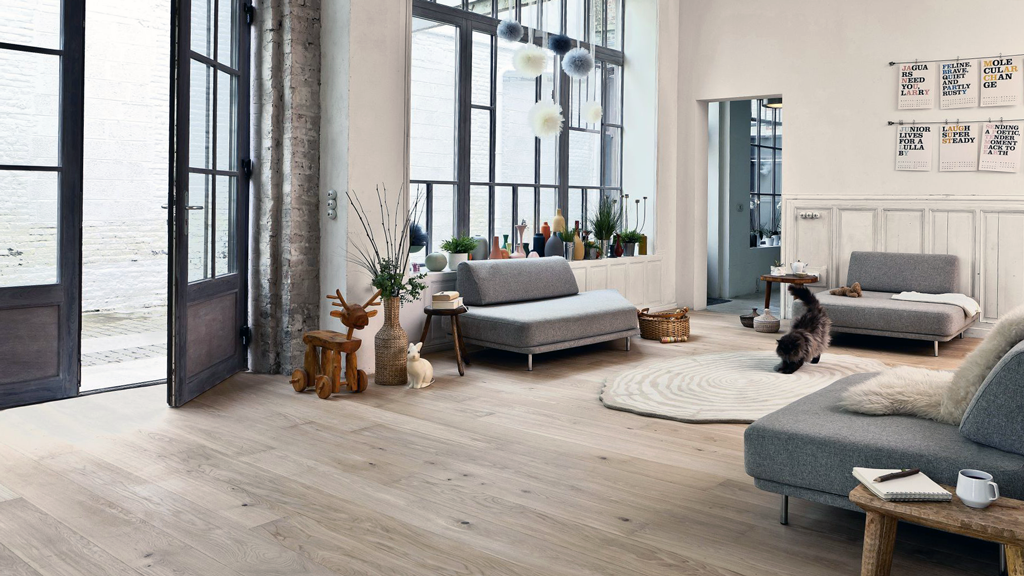 White oak hardwood floors highlight the simplistic and industrial styled living space where a fluffy cat makes his home.
