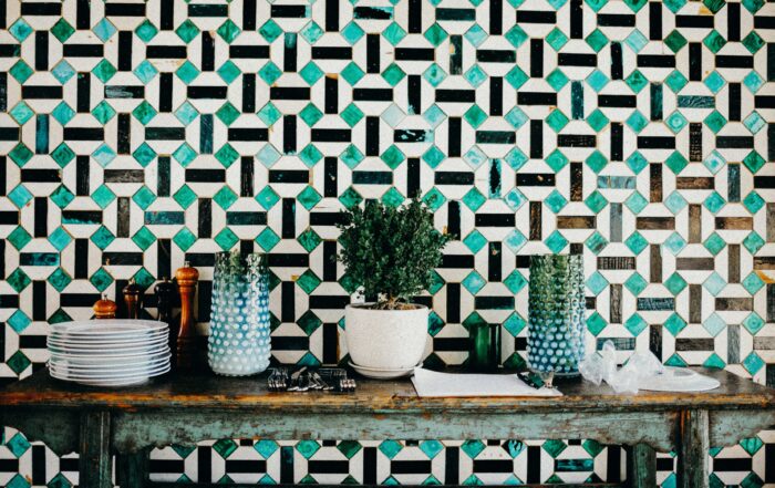 green brown and beige geometric floor tiles adorn this wall in an alternating pattern where 4 cacti highlight its natural design.